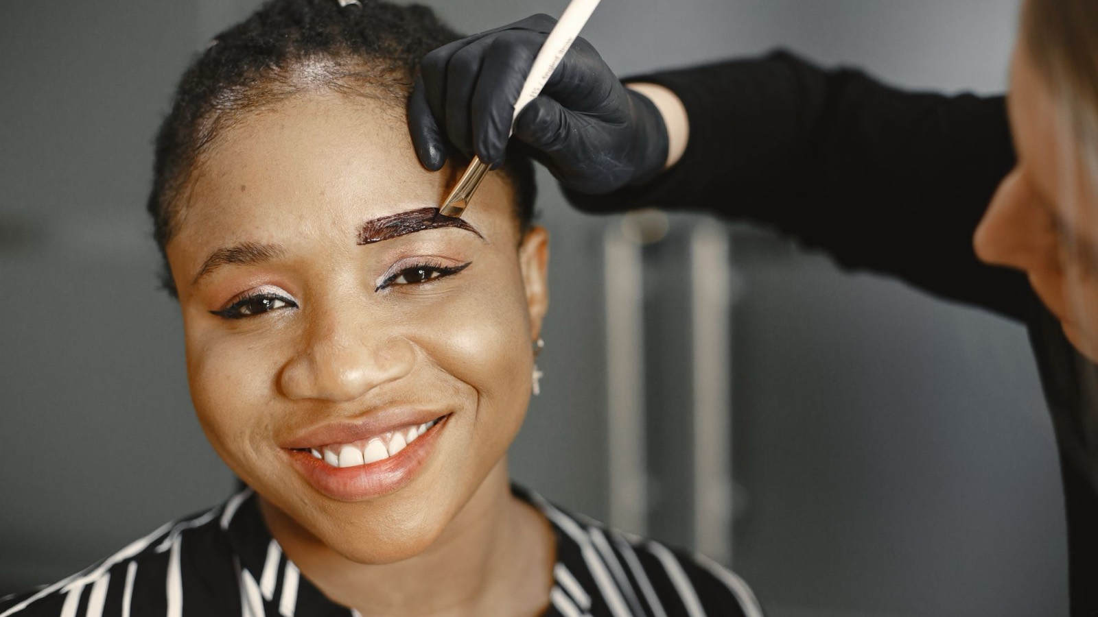 A brow artist shaping and tinting a client’s brows